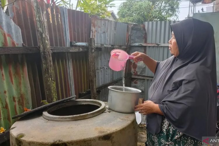 Susiyatin, warga Kelurahan Siantan Hilir, Kota Pontianak mengambil air hujan dari tempayan sebagai sumber air bersih untuk menanak nasi